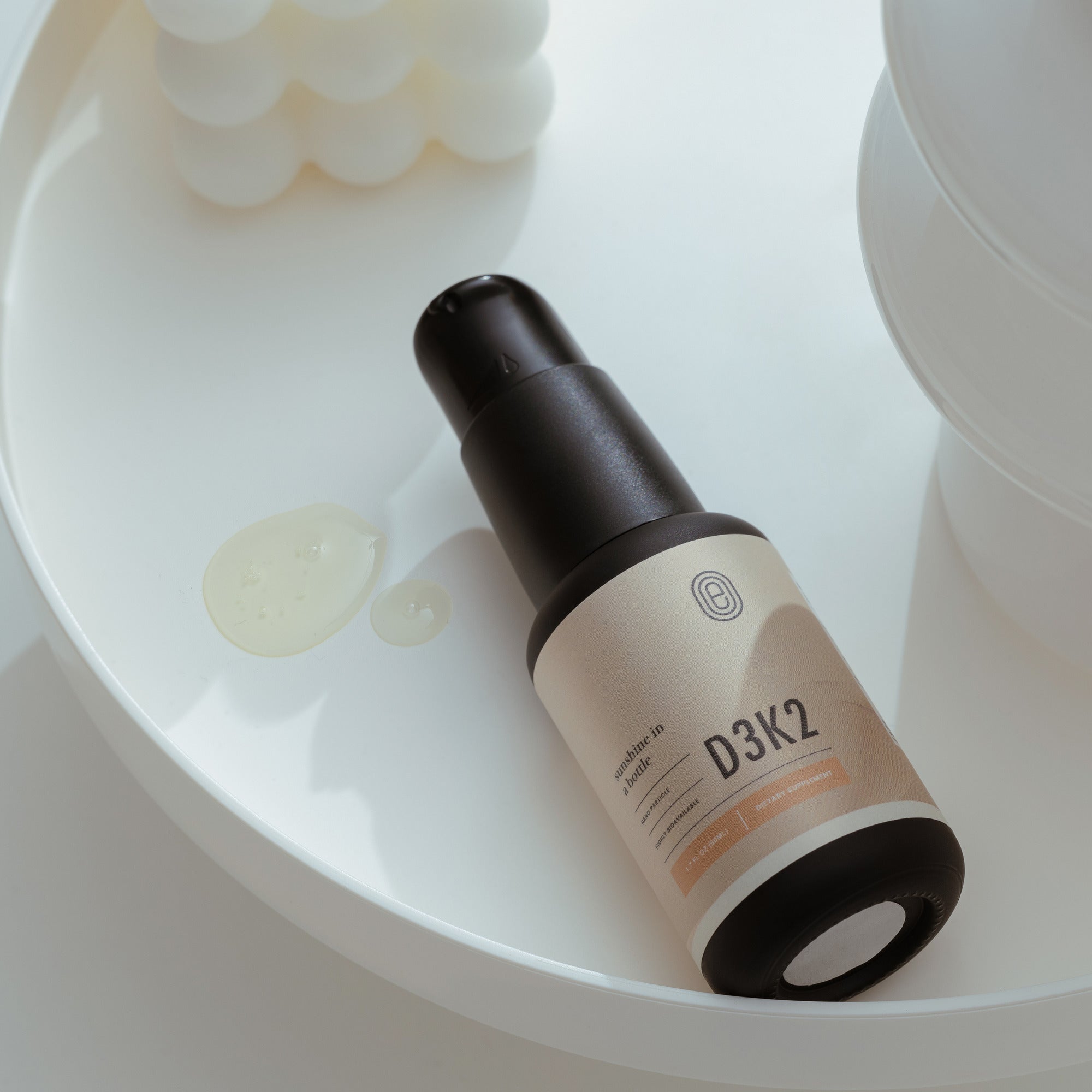 D3K2 liposomal vitamin supplement bottle promoting bone health on a white tray